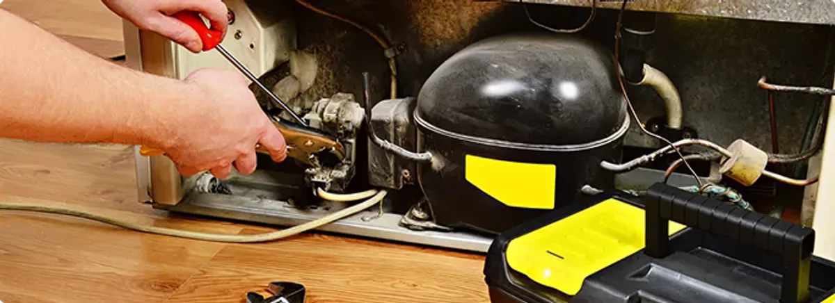 Refrigerator repair technician fixing the compressor and wiring in Carmel, IN