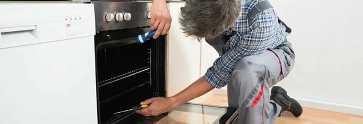 Oven repair technician inspecting and servicing an electric oven in Indianapolis, IN